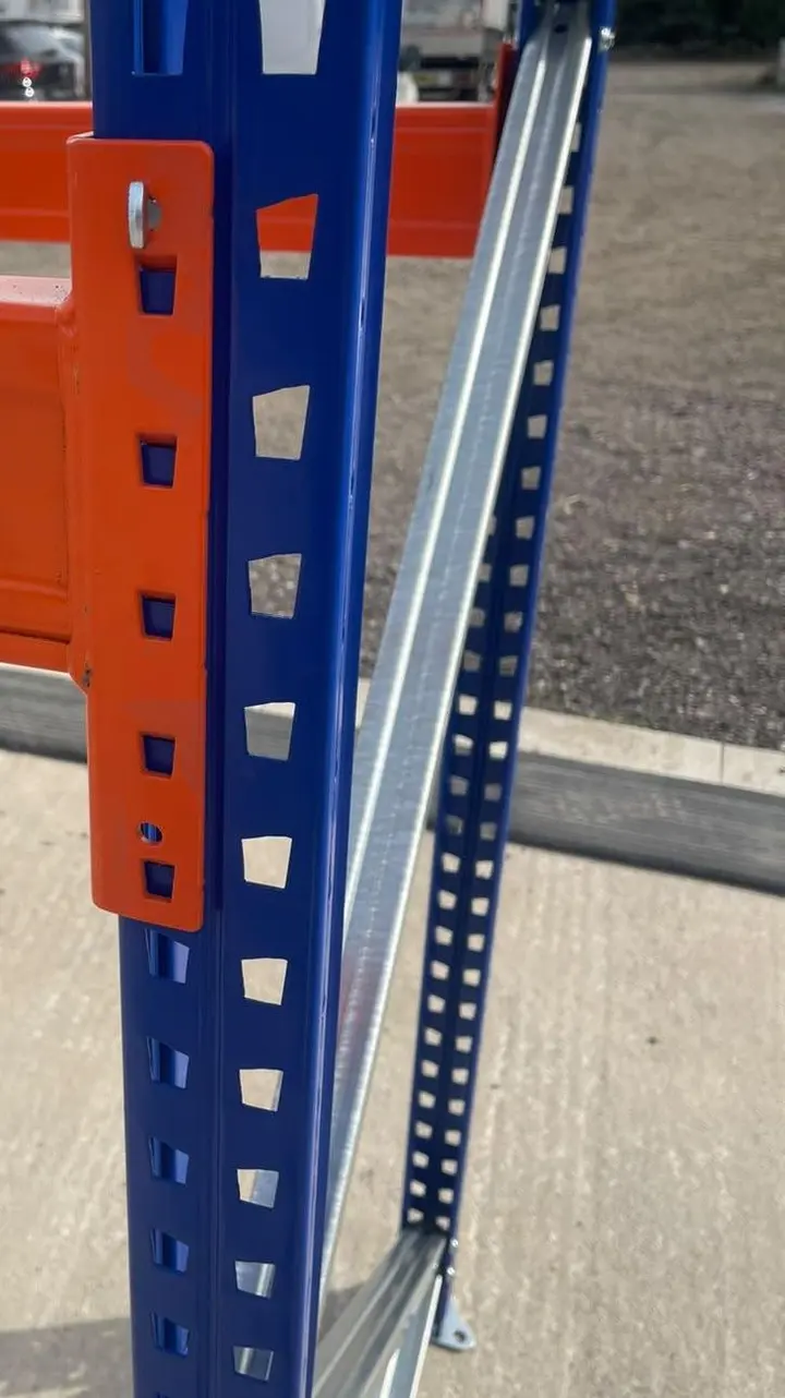 An orange beam connector on a blue upright, with bracing behind.