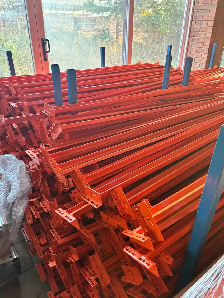 Bundles of orange racking beams with their connectors, stacked in store.