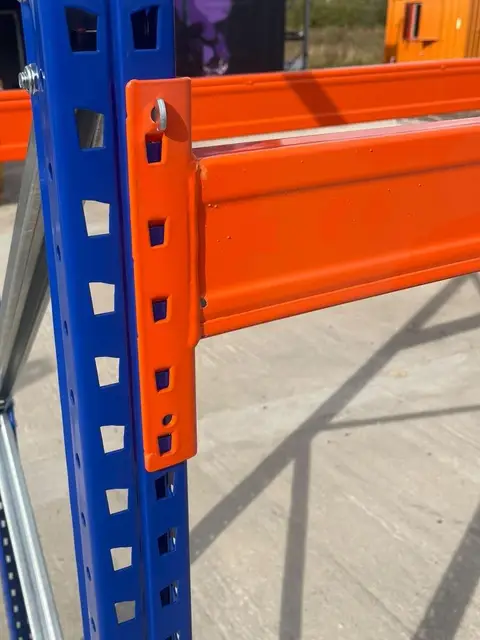 An orange beam connector on a blue pallet racking upright.